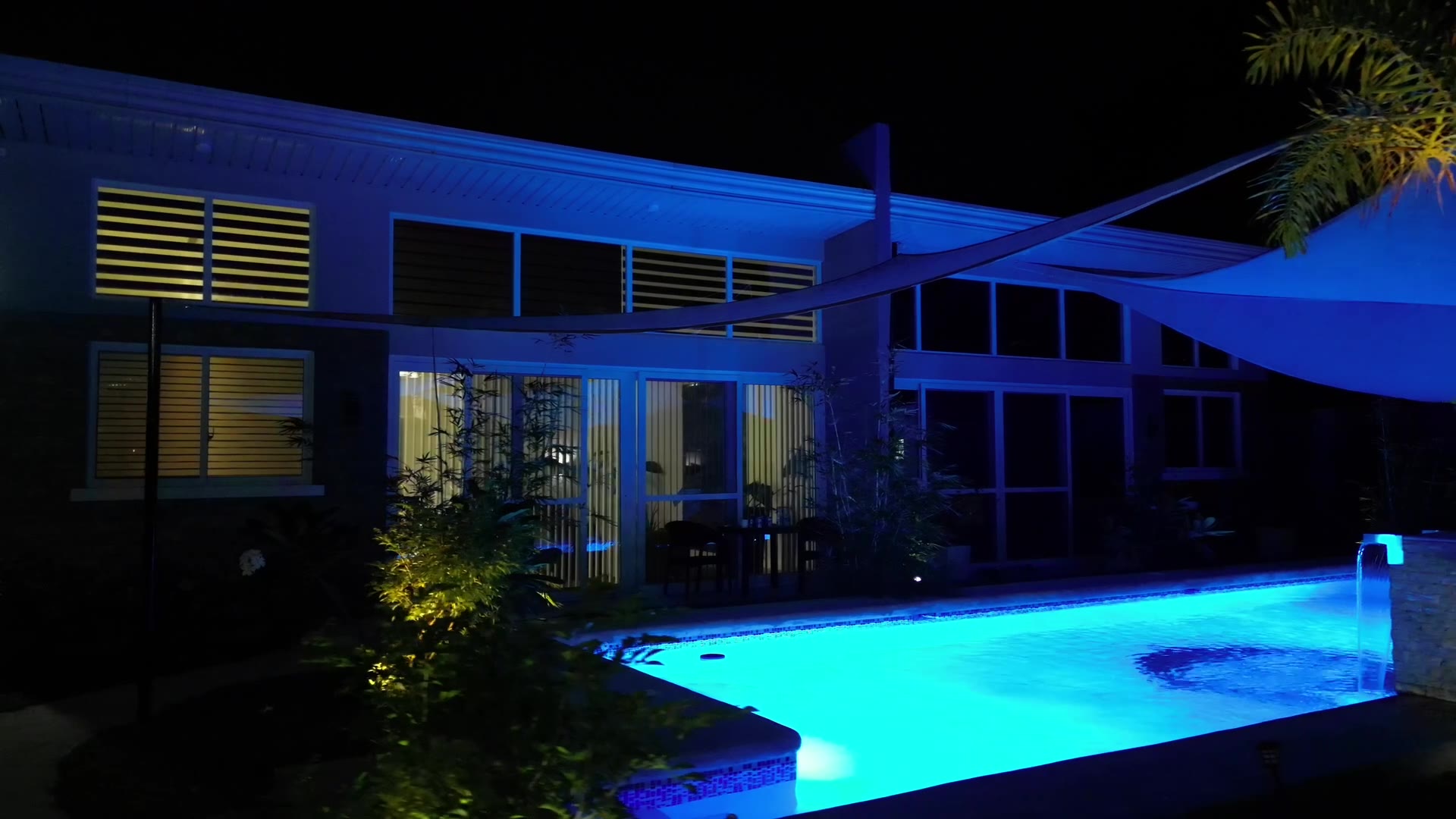Pool and house at night with shade sails